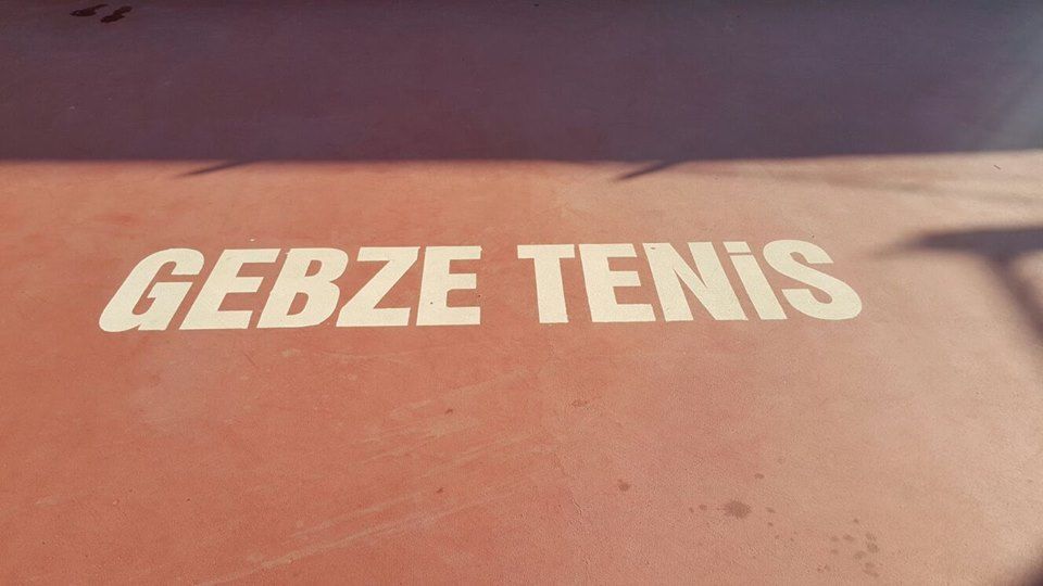 Kort zemininde beyaz harflerle yazılmış ‘Gebze Tenis’ yazısı
